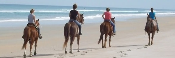 people horseback riding on the beach